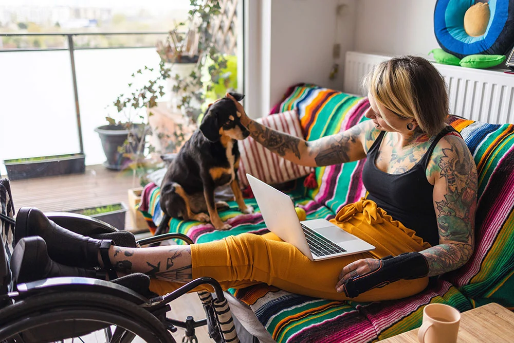 Woman using a laptop at home while petting her dog, symbolizing financial flexibility and independence through Unlock’s home equity solutions.