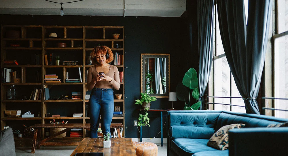 Photograph of a homeowner standing in a bright living room on the phone, representing how Unlock helps homeowners access home equity with clarity and confidence.